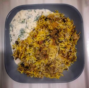 Hyderabadi Veg Dum Biryani and Raita in a plate